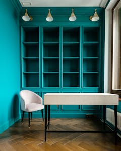 Photo by Sasha Pshenkov Elegant turquoise interior design featuring minimalist furniture with a wooden floor and natural lighting.