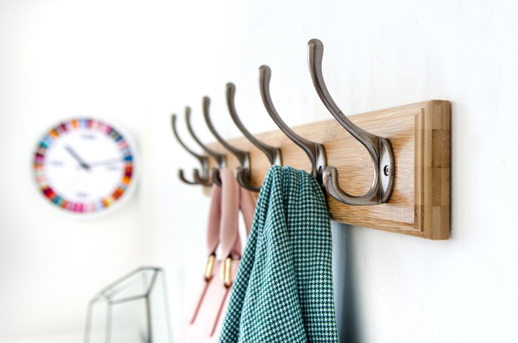 Over-door storage rack with hooks and shelves holding shoes, bags, and accessories in a small apartment